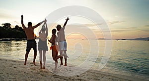 Group of friends having fun on the beach during sunset, having fun and jumping. Young people enjoying summer vacation