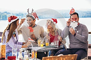 Group of friends having fun in cafe holding artificial mustache and lips stick