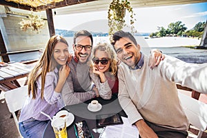 Group of friends having fun in cafe, make selfie photo.