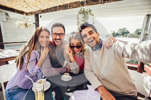 Group of friends having fun in cafe, make selfie photo