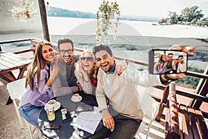 Group of friends having fun in cafe, make selfie photo