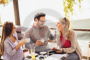 Group of friends having fun in cafe, using digital tablet