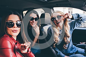 Group of friends having fun on the car. Singing and laughing in the city