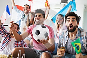 Group of friends having fun at home, watching game and enjoying together.