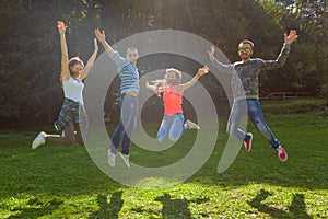 Group of friends having fun and jumping at idyllic sunny day