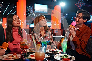 Group of friends having fun and singing songs at karaoke club