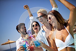 Group of friends having fun at summer party and drinking cocktail