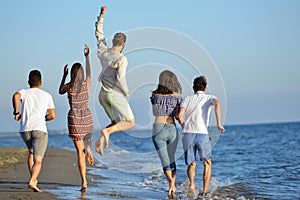 Group of friends having fun walking down the beach at sunset