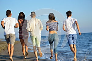 Group of friends having fun walking down the beach at sunset