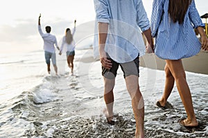 Group of happy friends having fun walking down the beach at sunset