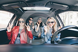 Group of friends having fun whet drive the car. Singing and laughing on the road