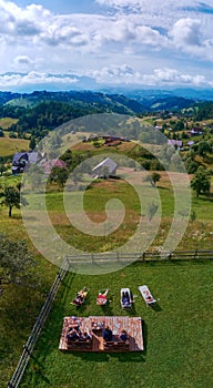 Group of friends having morning coffee in the backyard of a villa with a beautiful view over the valley and mountains in Magura, T