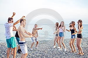 Friends dance on beach under sunset sunlight, having fun, happy, enjoy