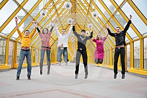 Group of friends jump on footbridge