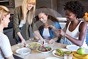 Group of friends laughing while eating healthy food at home.