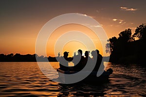 A group of friends laughing and joking in the boat during sunset