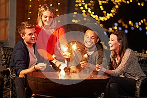 Group Of Friends Lighting Sparklers By Firepit photo