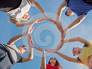A group of friends makes a circle from the palms of their hands