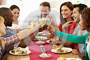 Group Of Friends Making Toast Around Table At Dinner Party