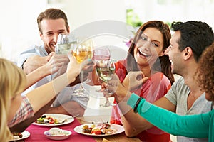 Group Of Friends Making Toast Around Table At Dinner Party