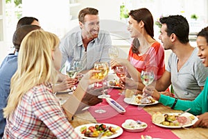 Group Of Friends Making Toast Around Table At Dinner Party