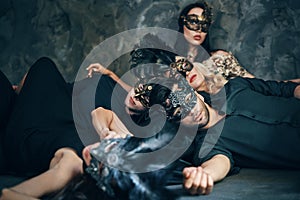 Group of friends in masquerade carnival mask sitting on floor relax after party