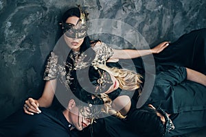 Group of friends in masquerade carnival mask sitting on floor relax after party