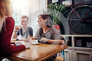 Group of friends meeting at cafe and drinking coffee or tea, chatting and laughing