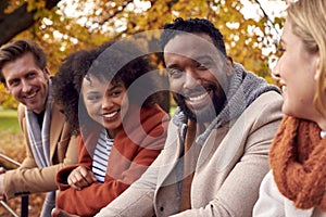 Group Of Friends Outdoors Wearing Coats And Scarves In Autumn Park