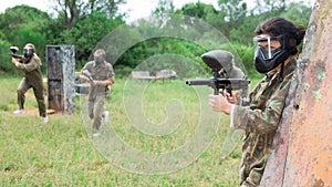 Group of friends paintball players of opposite teams in shootout in forest