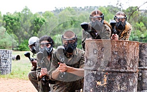 Group of friends paintball players of opposite teams in shootout in forest