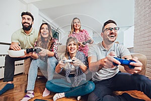 Group of friends play video games together at home