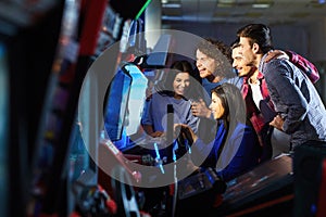 A group of friends playing arcade machine.