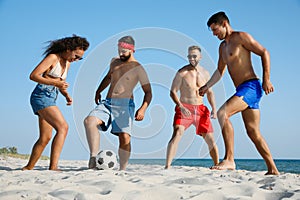 Group of friends playing football on beach