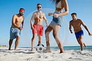 Group of friends playing football on beach