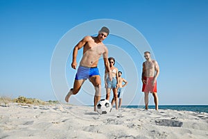 Group of friends playing football on beach