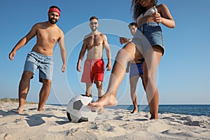 Group of friends playing football on beach