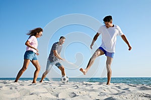 Group of friends playing football on beach