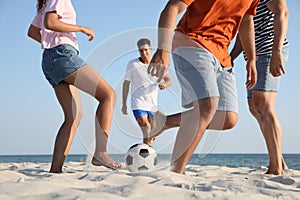 Group of friends playing football on beach, closeup