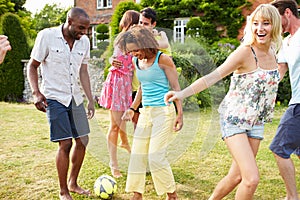 Group Of Friends Playing Football In Garden