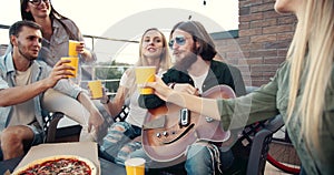 Group of friends playing guitar at party