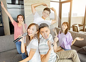 Group of friends playing karaoke at home