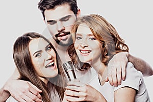 Group of friends playing karaoke over white background. Concept about friendship and people.