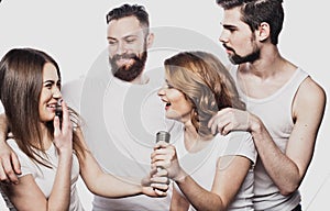 Group of friends playing karaoke over white background. Concept about friendship and people.