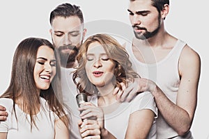 Group of friends playing karaoke over white background. Concept about friendship and people.