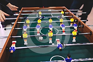 Group of friends playing kicker in a sports bar room, colleagues teammates play table football, table soccer game in the office,