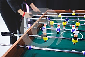 Group of friends playing kicker in a sports bar room, colleagues teammates play table football, table soccer game in the office,