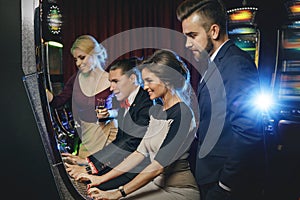 Group of friends playing slot machines in casino