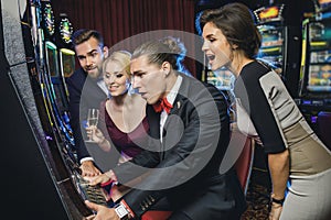 Group of friends playing slot machines in casino
