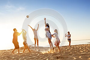 Group of friends plays ball sunset beach